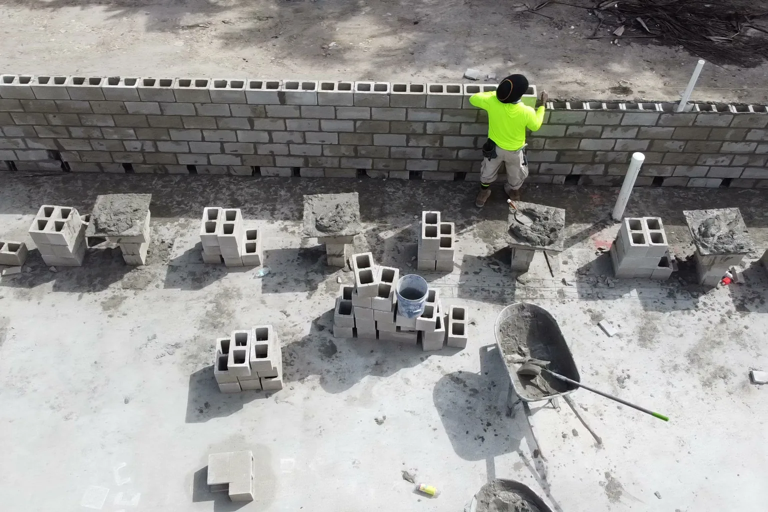 Aerial view of a mason laying concrete block on a finished slab