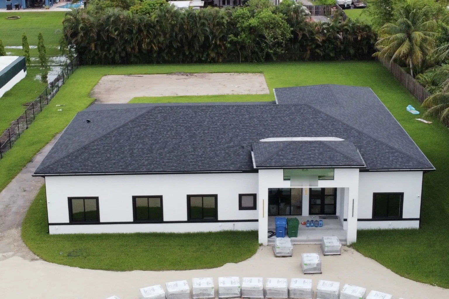 Aerial view of a finished Florida home, painted white with a new roof and sod