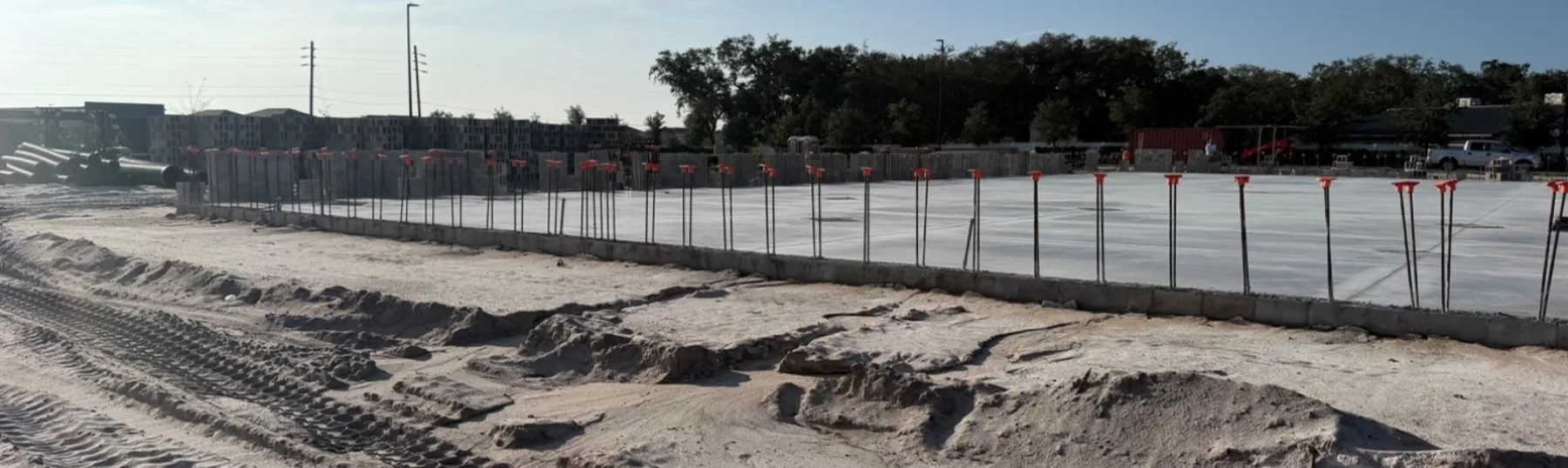 Poured and cured slab with vertical dowels standing along the perimeter and block delivered on the pad