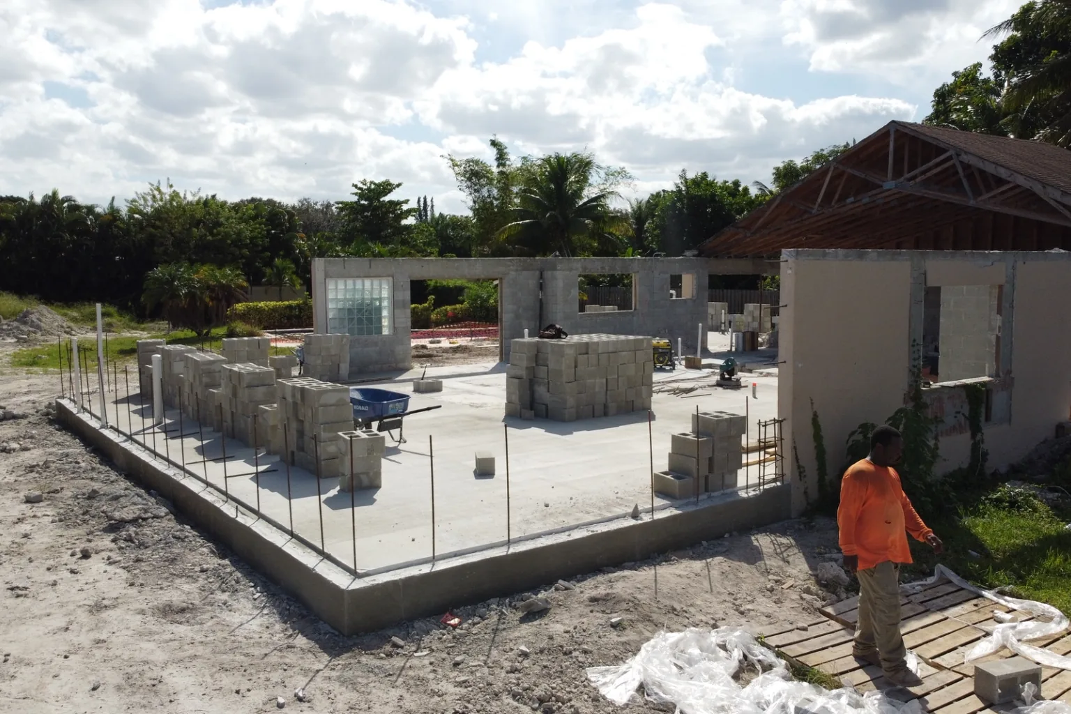 New block walls rising beside an existing stucco house